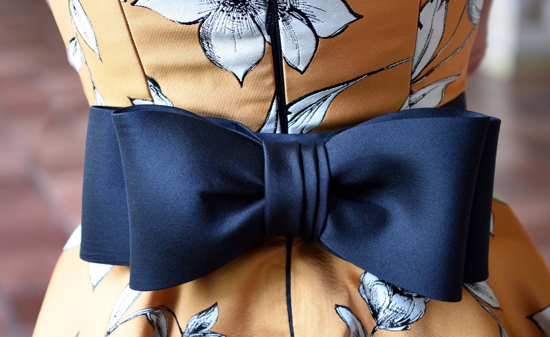 Orange dress with white floral detail and navy blue accent bow